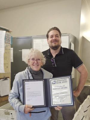 Postmaster Trevor Jacobs presents Valerie Percival Rural Mail carrier of Oxford Nebraska her 25 year service award. Valerie started carrying for the Postal Service in 1993 as a sub