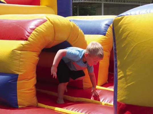 A Bartley child runs through one of the bounce houses offered to the community in the park during Bartley days.