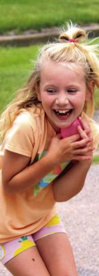 A girl laughs as she successfully catches her water balloon.