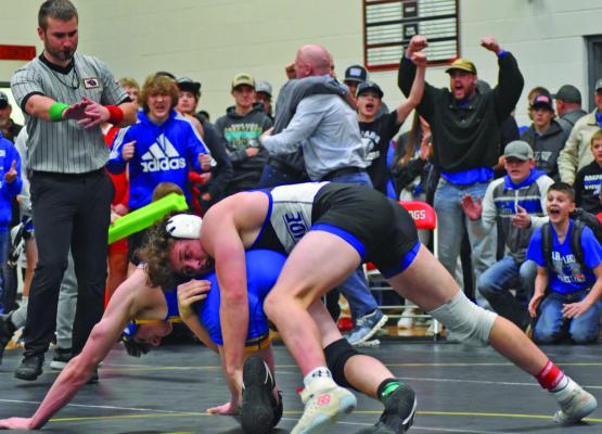 Coaches, teammates and fans of Arapahoe’s Grayson Koller celebrate his semifinal win at districts Saturday as he clinches his first berth at the State Tournament.