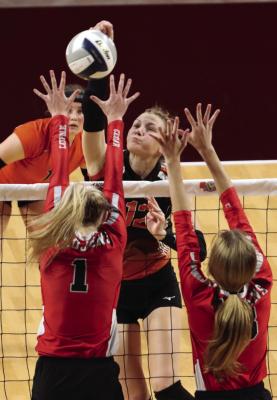 Cambridge’s Erin Johnson (above) slams a kill while the Trojans’ Breelle Miller (below) sets a teammate.