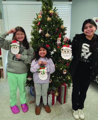 The Oxford Public Library held their story hour with a Christmas theme on Friday, December 13. There were snacks, ornament making, and a story. These three proudly show off their crafting abilities.