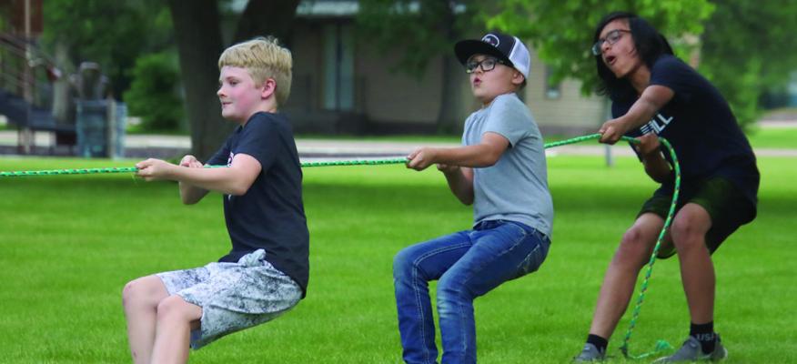 Three friends try their hardest in beating the other team during their go at tug-of-war.