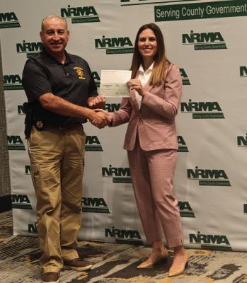 Gosper County Sheriff Jesse Naputi receives a dividend check presented by NIRMA board of directors member Bonnie Moore of the Sarpy County Attorney’s Office.