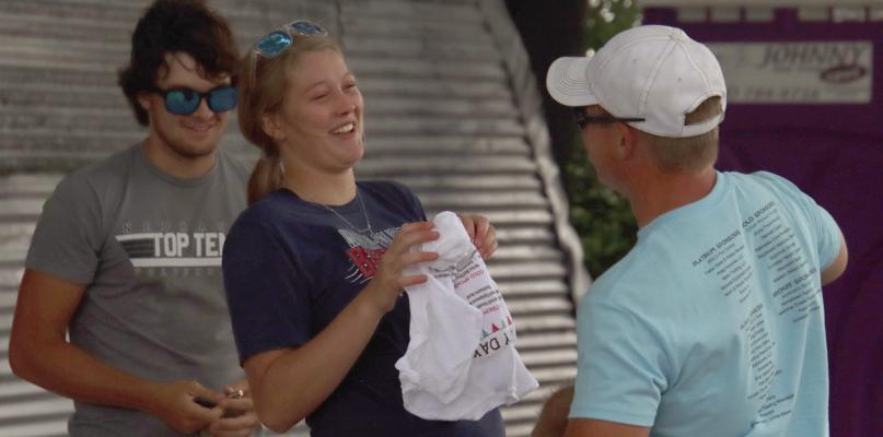 Participants of the wet t-shirt contest chat as they pull apart fabric during the competition.
