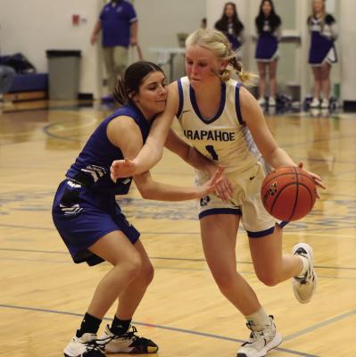 Right: Warrior Emma Strand drvies past a Wallace defender in the first game of the Arapahoe Holiday Tournament.