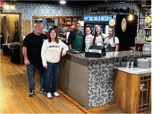 Jeff and Julie Sherwood stand at the bar with the staff of their new restaurant, Woody’s Grill &amp; Chill in Oxford. Woody’s is in the former Kuch’s Lounge.