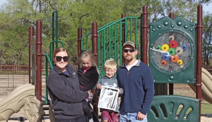 Miranda and Tanner Teel used memorial money from the loss of their baby Warner to help construct a playground at the ballpark in Indianola. They’re pictured with their children, Vivian and Dierks, and a picture of Warner.