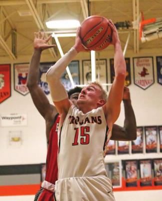 The Trojans’ Derek Trompke powers up for a fast break layup chance against Coazad.