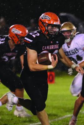 Cambridge’s Tye Stanton weaves through traffic and rain drops on a run riday night.