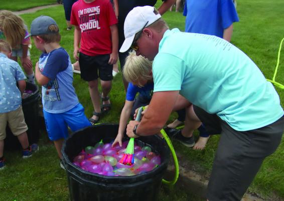 Kids watch excitedly for all water balloons to be filled in anticipation for the activity.