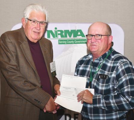 Gosper County Highway Superintendent Michael Snyder accepts the county’s financial dividend from NIRMA Board of Directors member Larry Cerny, a Fillmore County supervisor.