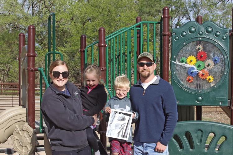 Miranda and Tanner Teel used memorial money from the loss of their baby Warner to help construct a playground at the ballpark in Indianola. They’re pictured with their children, Vivian and Dierks, and a picture of Warner.