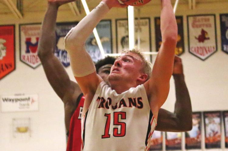 The Trojans’ Derek Trompke powers up for a fast break layup chance against Coazad.