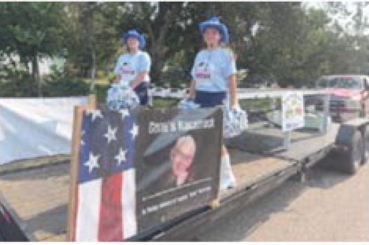 The Southwest Cheerleaders on the Old Settlers day toy tractor float. This Toy Tractor table was made in Memory of Gene Anderson who was in the Tractor Club.