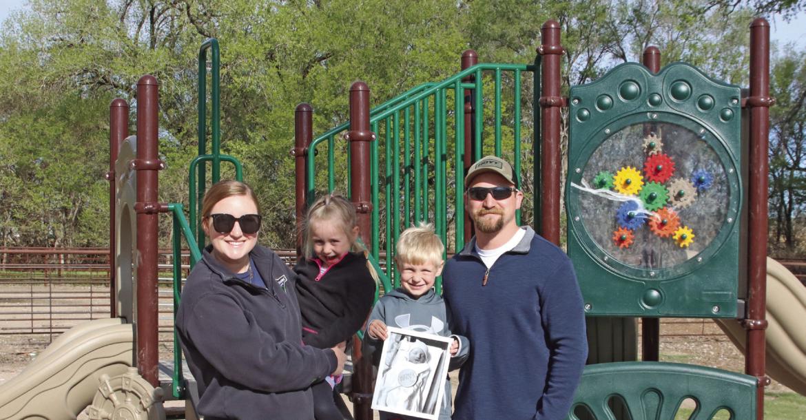 Miranda and Tanner Teel used memorial money from the loss of their baby Warner to help construct a playground at the ballpark in Indianola. They’re pictured with their children, Vivian and Dierks, and a picture of Warner.